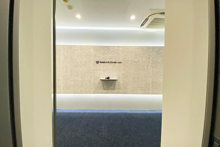 濃いネイビーと間接照明で仕上げたオフィスエントランス